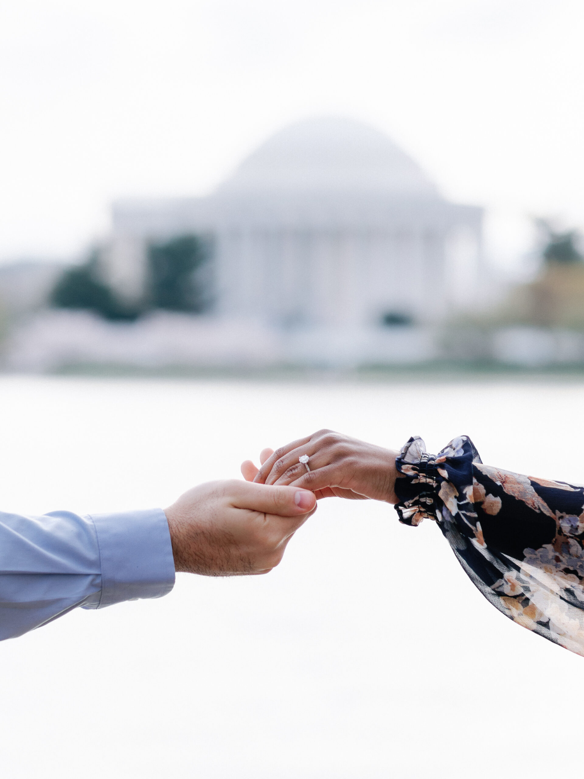 A couple holding hands in front of the jefferson memorial.