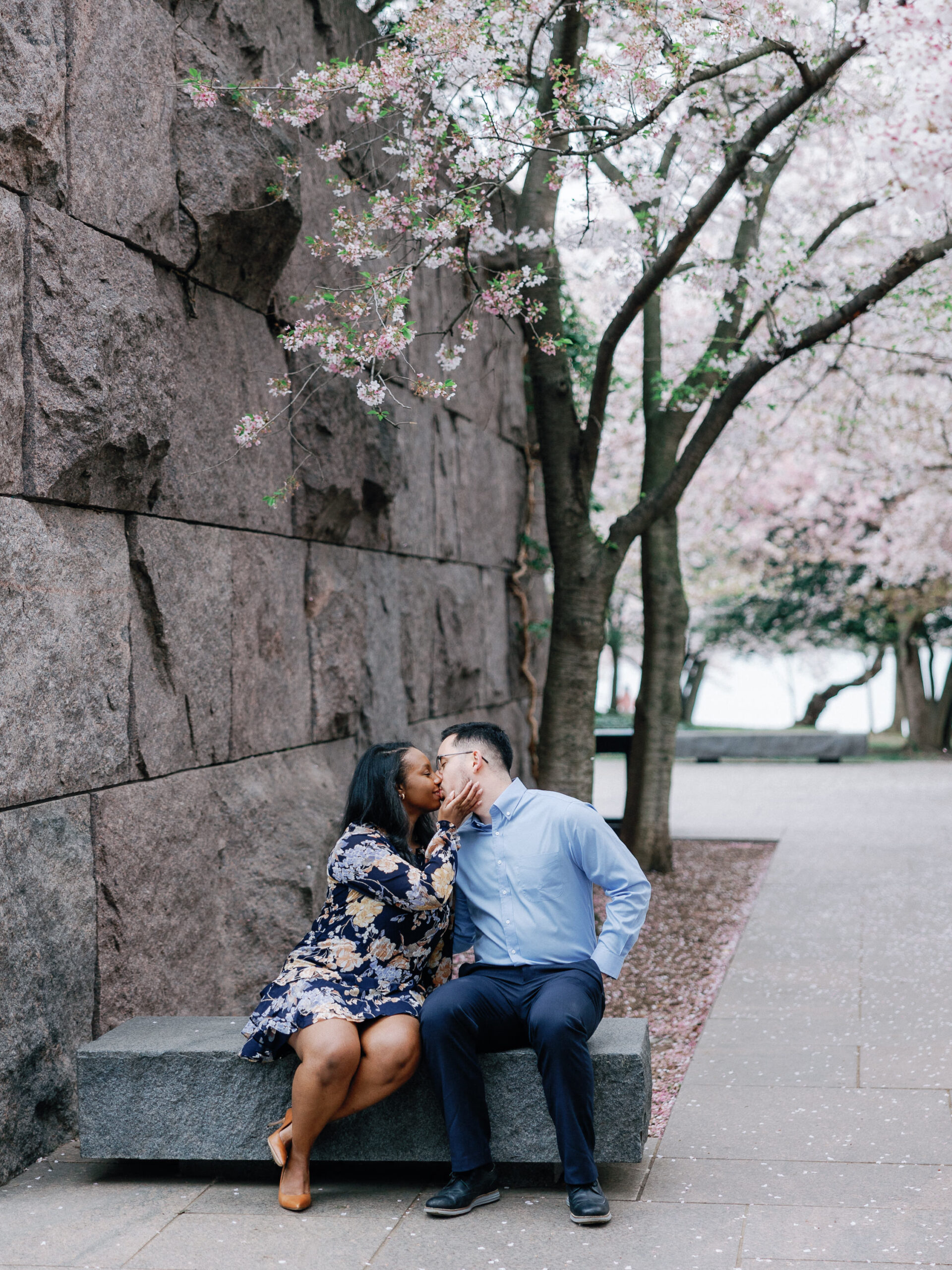A couple sharing a kiss along the Tidal Basin in DC during the cherry blossom bloom.